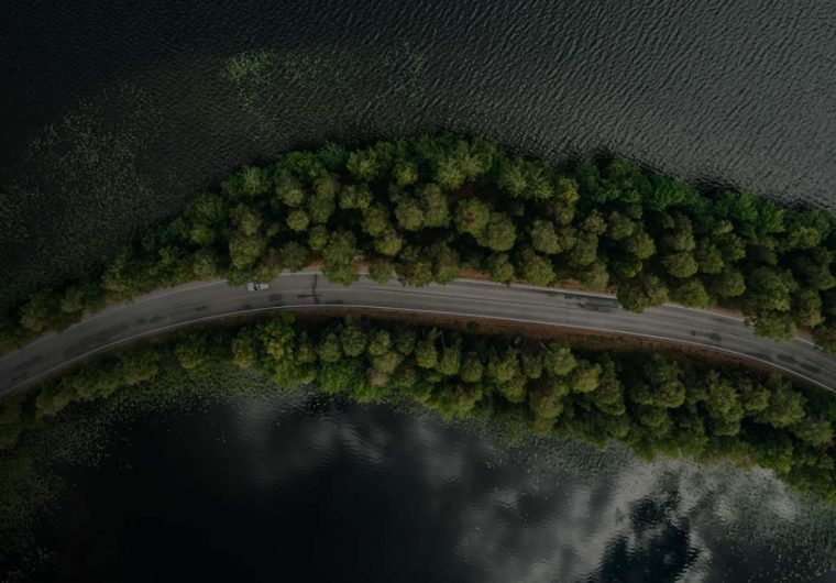 A background image for EV Universe of a car driving on an empty road.